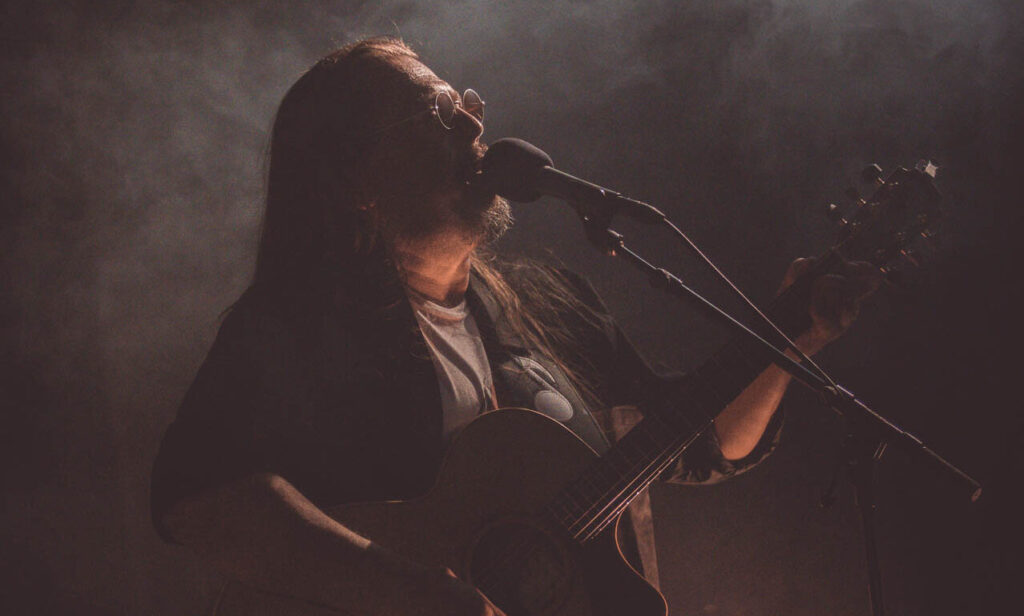 singender Musiker mit einer Gitarre auf der Bühne
